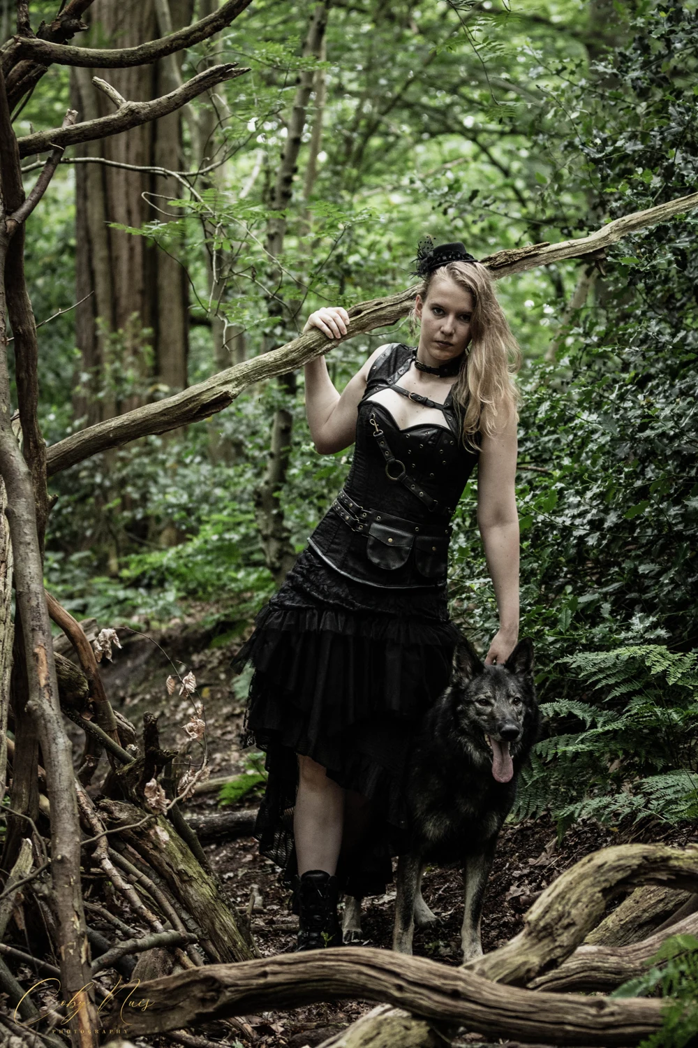 Melissa Kortekaas in een zwart jurkje tussen de bomen in het bos