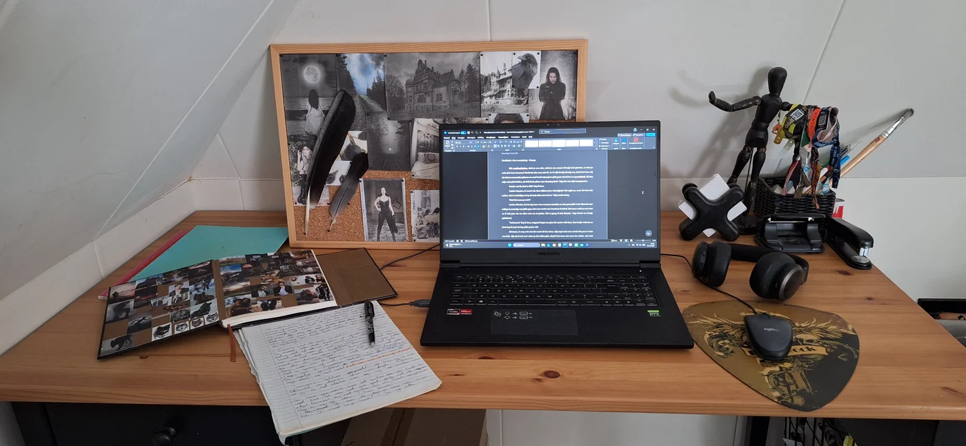 Houten schrijftafel met een laptop, een open schrift, notitieboeken en inspiratiebeelden